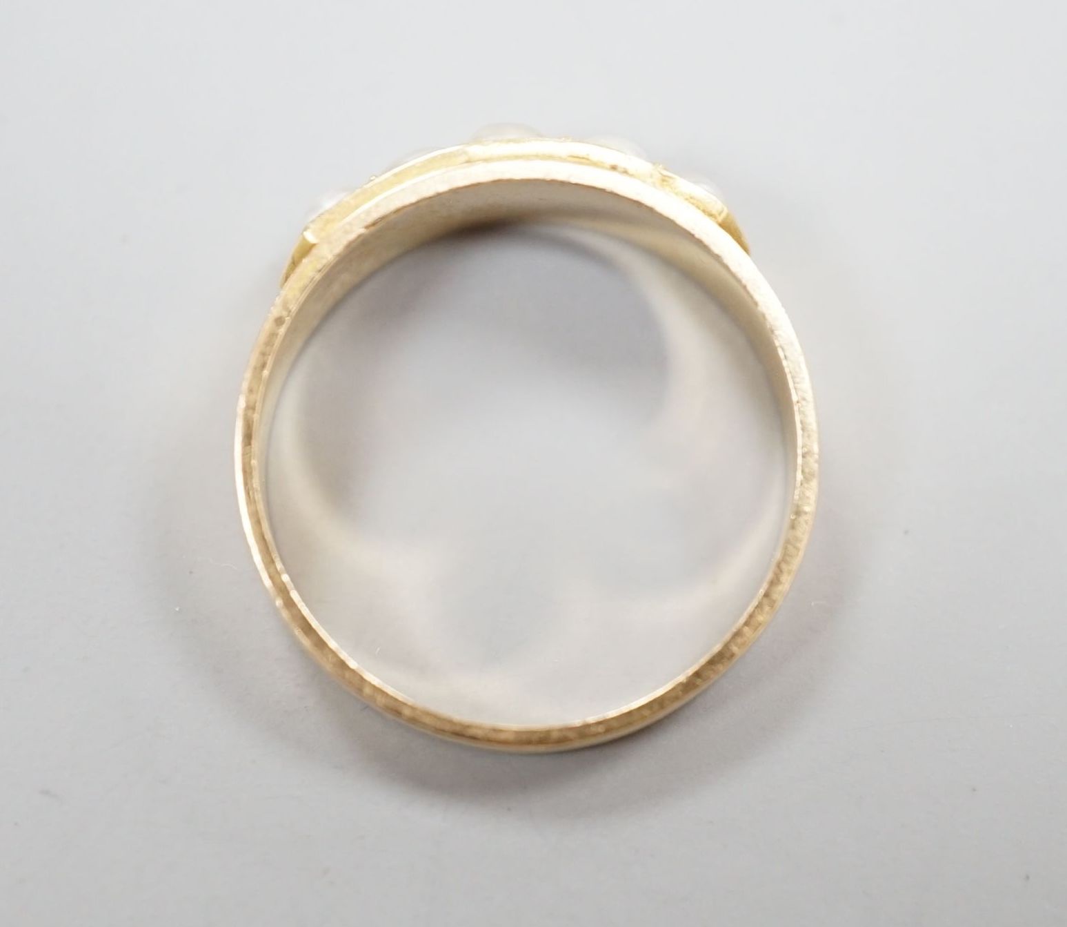 A yellow metal and graduated five stone split pearl set half hoop ring, size M, gross 3 grams.